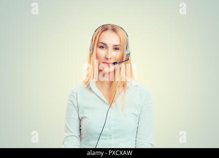 Young blonde in white shirt and headset working in call center and looking at camera Stock Photo