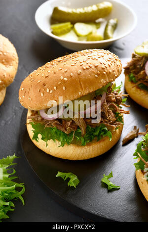 Pulled beef sandwich with vegetables on black wooden board Stock Photo