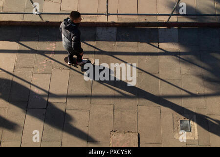 A skateboarder casts a long shadows on an autumnal afternoon Stock Photo