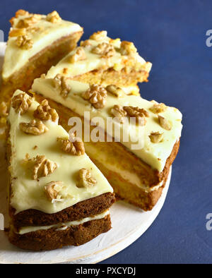 Close up of sliced carrot cake on blue stone background. Tasty homemade baking. Stock Photo
