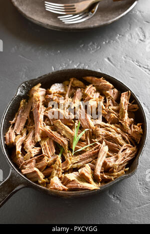 Slow cooked beef for sandwiches in frying pan on black stone background. Stock Photo