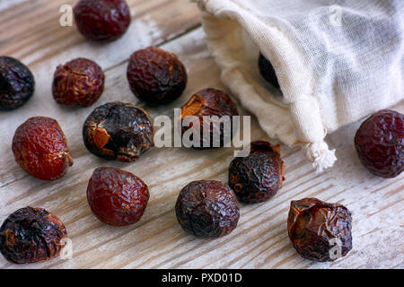 Soap nuts spilling from textile bag on wooden background. Close-up. Stock Photo