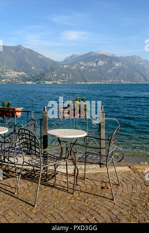 wrought iron chairs and table on lake side of Como lake , shot in bright fall light at Menaggio, Como, Italy Stock Photo