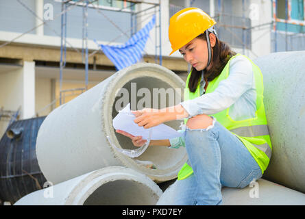 Woman engineers looking blueprint at construction site Stock Photo