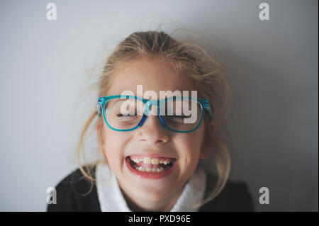 funny delightful face of little laughing caucasian girl in blue glasses Stock Photo