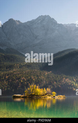 Maximilian Island in the LakeEibsee in front of the rock wall and summit of the Zugspitze in the Wetterstein Mountains in autumn, Bavaria, Germany Stock Photo