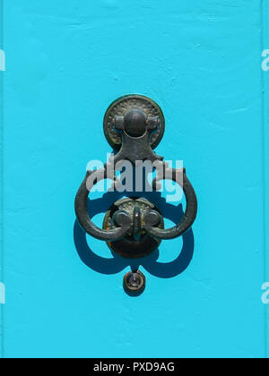 Ancient wrought iron door knocker on a blue background Stock Photo