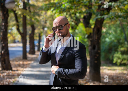 A handsome young businessman talking on his phone in the park Stock Photo