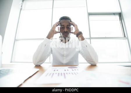 Puzzled African businessman analyzing graphs Stock Photo