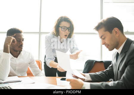 Shocked lady showing report to colleague Stock Photo