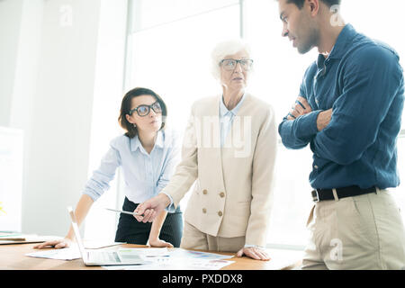 Senior lady explaining analytical data to colleagues Stock Photo