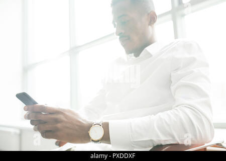 Carefree businessman using smartphone in office Stock Photo