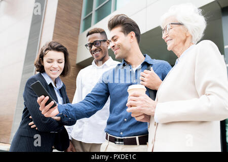 Cheerful colleagues using convenient mobile app for business Stock Photo