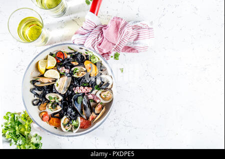 Homemade seafood Black pasta spaghetti with clams mussels octopus vongole in pan with white wine on marbled background Stock Photo
