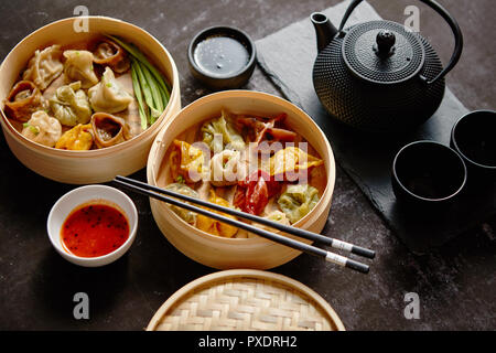 Composition of chinese food. Mixed kinds of dumplings from wooden bamboo steamer Stock Photo
