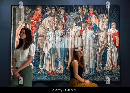 London, UK.  22 October 2018. Staff members sit next to 'The Holy Grail Tapestries:  The Arming and Departure of the Knights of the Round Table on the Quest for the Holy Grail', 1890-94, by Edward Burne-Jones. Preview of the largest Edward Burne-Jones retrospective to be held in a generation at Tate Britain.  Burne-Jones was a pioneer of the symbolist movement and the only Pre-Raphaelite to achieve world-wide recognition in his lifetime.  The exhibition runs 24 October to 24 February 2019.  Credit: Stephen Chung / Alamy Live News Stock Photo