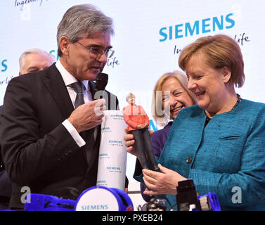 Hanover, Germany. 24th Apr, 2017. German chancellor Angela Merkel (R) looks at a figure replica of herself made by a 3D Printer of Siemens during the opening round tour at the Hanover Fair 2017 in Hanover, Germany, 24 April 2017. Joe Kaeser (L), chairman of Siemes looks on in glee. The world's biggest industry trade fair will see some 6500 exhibitors from the 24th to the 28th of April. The partner nation of this year is Poland. Credit: Julian Stratenschulte/dpa | usage worldwide/dpa/Alamy Live News Stock Photo