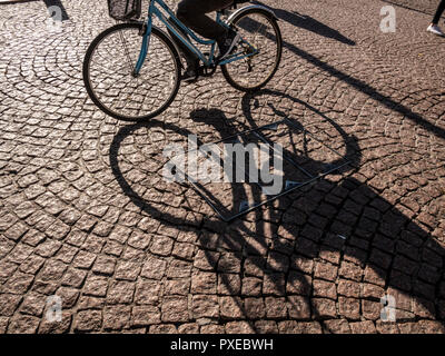 Cambridge, UK. 22nd Oct, 2018. Dazzling autumn sunshine creates strong shadows and contrast on a crisp, clear sunny day. The city is famous for cycling and the sun created deep shadows of cyclists on the cobbled streets. The beautiful weather is et to continue in the East of England. CreditL Credit: Julian Eales/Alamy Live News Stock Photo