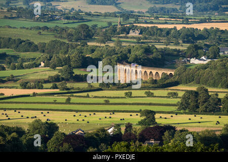 High view across farmland fields in Wharfedale valley to Arthington Viaduct (with train crossing) on sunny summer day - North Yorkshire, England, UK. Stock Photo