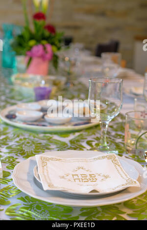 Modern Passover Seder table with green  and gold decorations in Tel Aviv, Israel, complete with holiday napkins saying "Happy Passover" in Hebrew Stock Photo