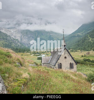 View on the quaint church of Gletsch with misty mountains in the background, Saturday 20 August 2016, Gletsch, Switzerland. Stock Photo