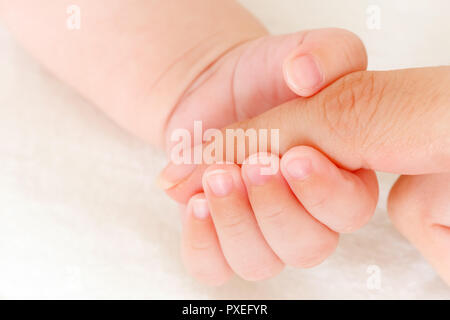 Close-up of baby's hand holding mother's finger Stock Photo