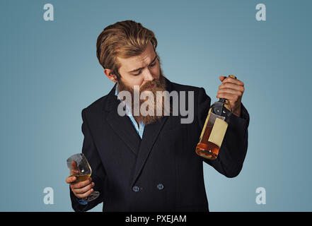 Nice choice. Man holds looks at bottle of cognac whiskey alcohol drink. Social and cultural aspects of drinking. Man thoughtful estimating bottle alco Stock Photo