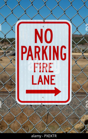No parking fire lane sign on fence in parking lot Stock Photo