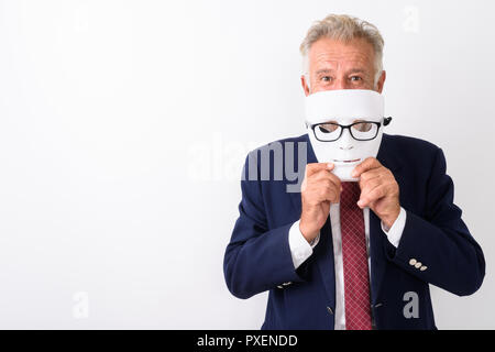 Studio shot of handsome senior bearded businessman hiding behind Stock Photo