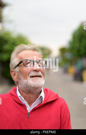Happy handsome senior bearded man smiling while thinking and loo Stock Photo