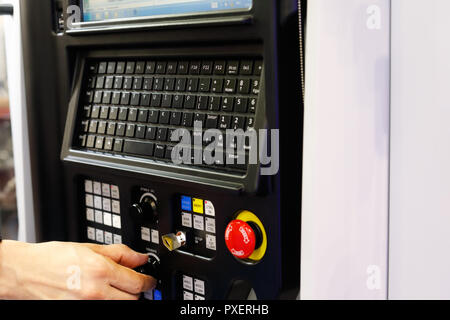 Operator working with CNC lathe machine using control panel. Selective focus. Stock Photo