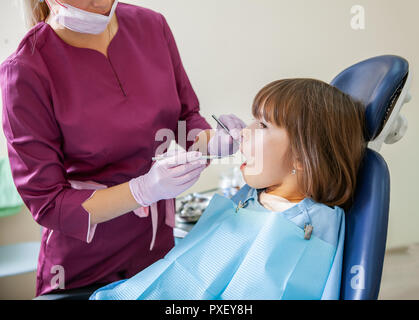 Female dentist in dental office treats teeth with kid patient Stock Photo