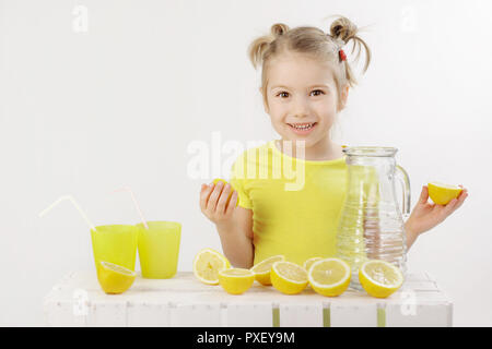 'When life gives you lemons make a lemonade' Five-year-old girl holding lemons making lemonade isolated on the white background. Stock Photo