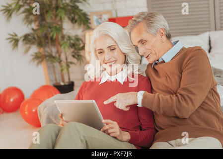 Happy elderly married couple sitting together and using the tablet Stock Photo