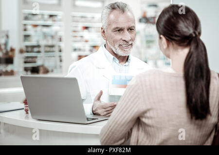 Bearded pharmacist feeling involved in giving recommendations to his client Stock Photo