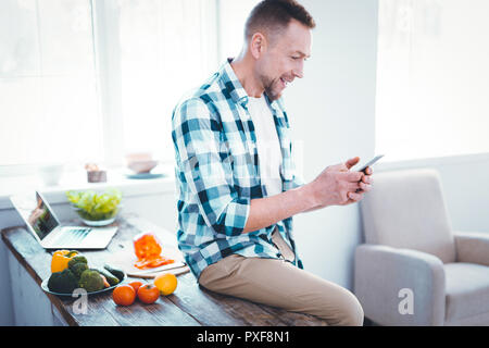 Joyful nice positive man using social media Stock Photo