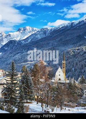 Winter landscape with small Church (Reformierte Kirche Scuol) in front of the mountains, Scuol , Lower Engadine, Switzerland. Stock Photo