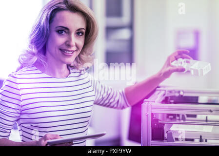 Beautiful blonde-haired interior designer standing near printer working on sketches Stock Photo