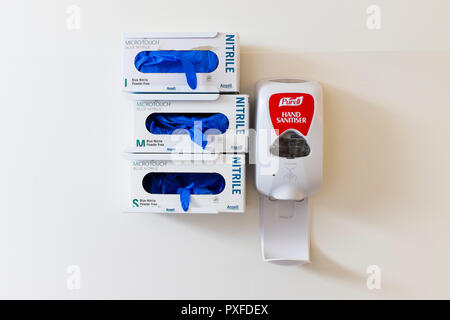 Disposable gloves and hand sanitiser mounted on wall in emergency department in hospital in Australia, Oct 2018 Stock Photo