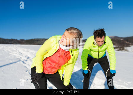 Senior couple runners resting in winter nature in snow. Copy space. Stock Photo