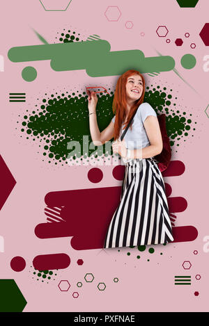Fashionable student wearing striped skirt standing ahead of bright colorful ground Stock Photo