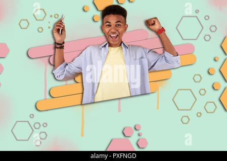 Happy mulatto boy feeling extremely cheerful after winning prize in online game Stock Photo
