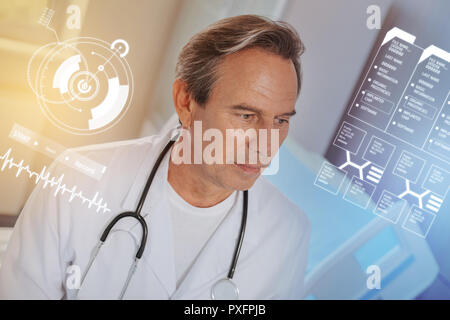 Calm middle aged doctor wearing a white coat and looking thoughtful Stock Photo