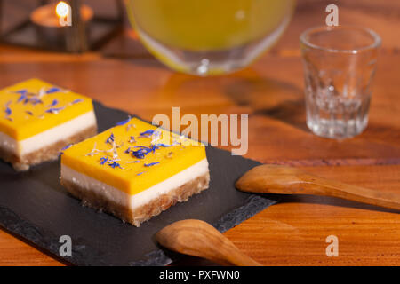 homemade lime and mango cake on a black stone plate with wooden spoons Stock Photo