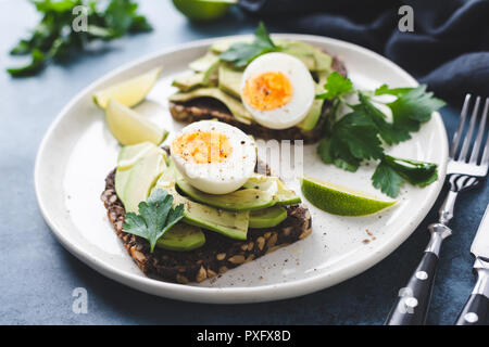 Healthy rye toast with avocado, egg, feta cheese on plate, closeup view. Breakfast, snack or lunch food Stock Photo