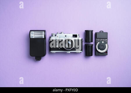 Analog camera and other accessories over purple background Stock Photo