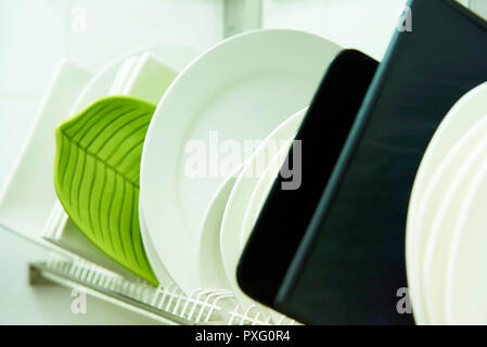 Different clean plates in dish drying rack close-up. Stock Photo