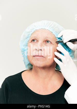 The surgeon doing skin check on mid age woman before plastic surgery. Senior female model. plastic surgery, lifting, aging concept Stock Photo