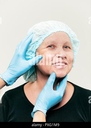 The surgeon doing skin check on mid age woman before plastic surgery. Senior female model. plastic surgery, lifting, aging concept Stock Photo