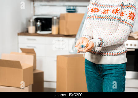 cropped image of woman holding keys in kitchen with cardboard boxes at new home Stock Photo